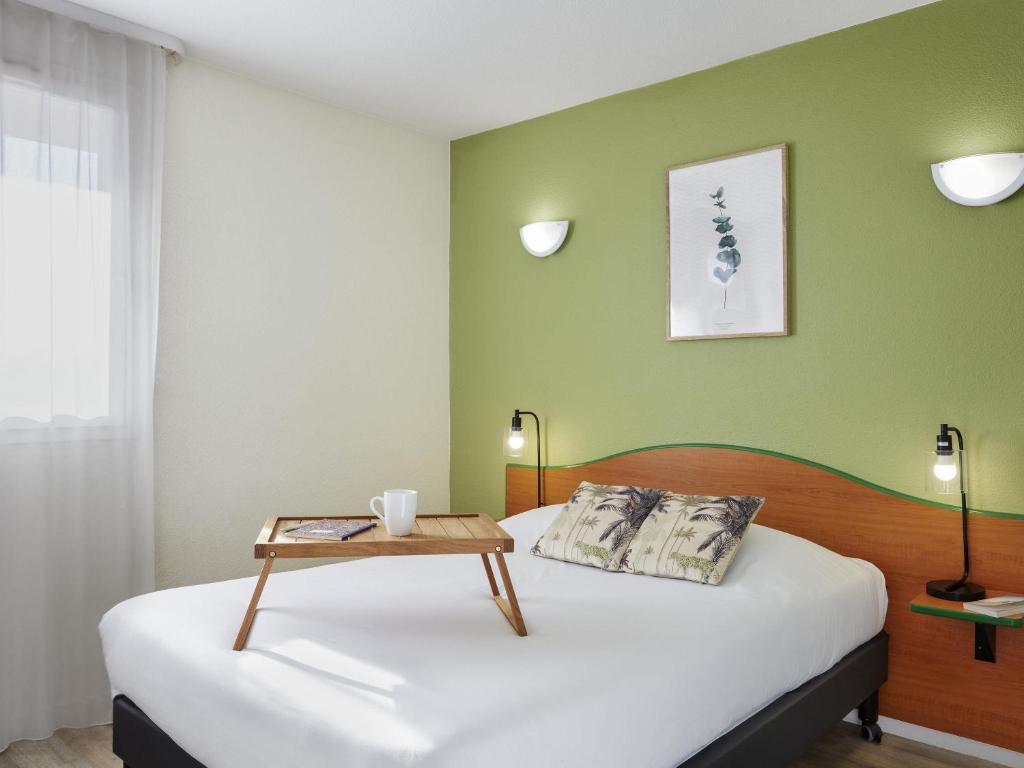 a bedroom with two beds and a table on the bed at Aparthotel Adagio Access Bordeaux Rodesse in Bordeaux