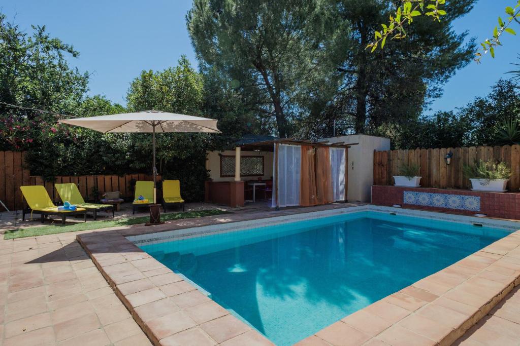 a swimming pool in a backyard with an umbrella at El Grifo Casa De Campo Con Piscina in Carmona
