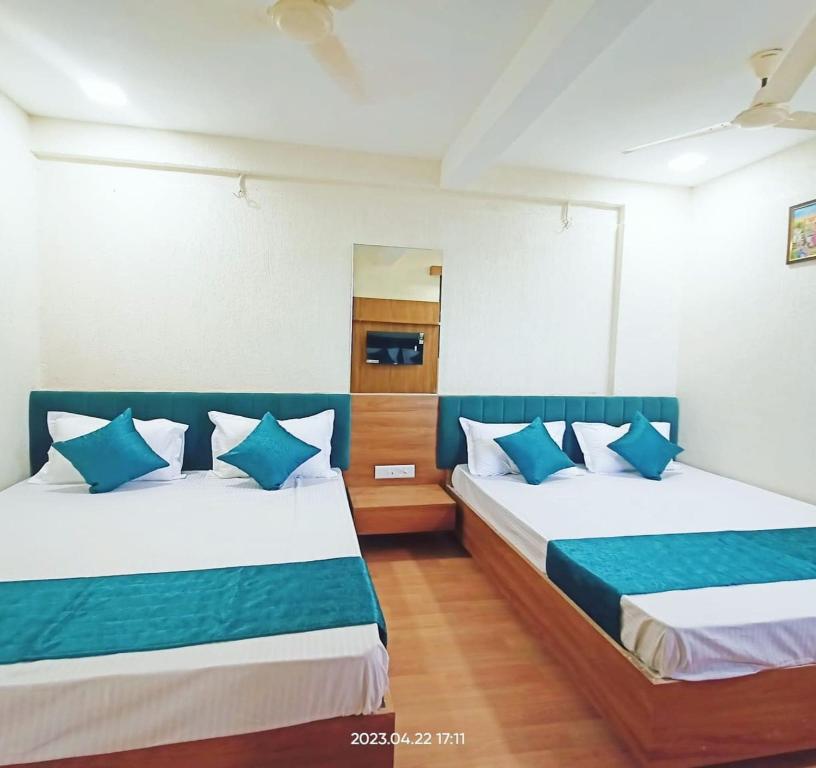 a bedroom with two beds with blue and white pillows at Hotel shree Tapovan in Ahmedabad