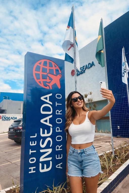 a woman standing in front of a sign at Hotel Enseada Aeroporto in Recife