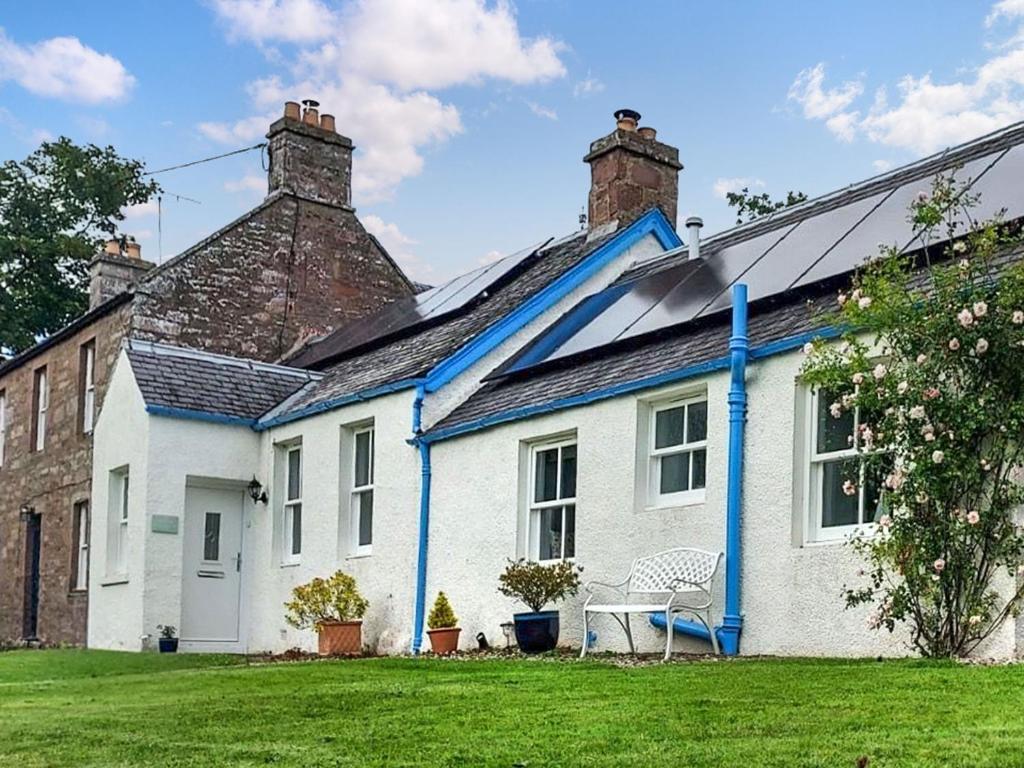 a white and blue house with a chair in the yard at The Old School House Cottage in Coupar Angus