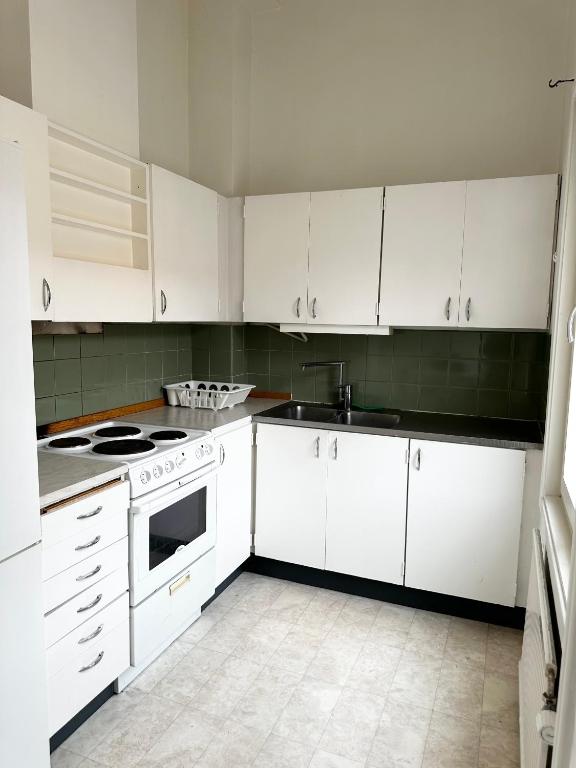 a kitchen with white cabinets and a stove top oven at Lägenhet Centrum Karlshamn in Karlshamn