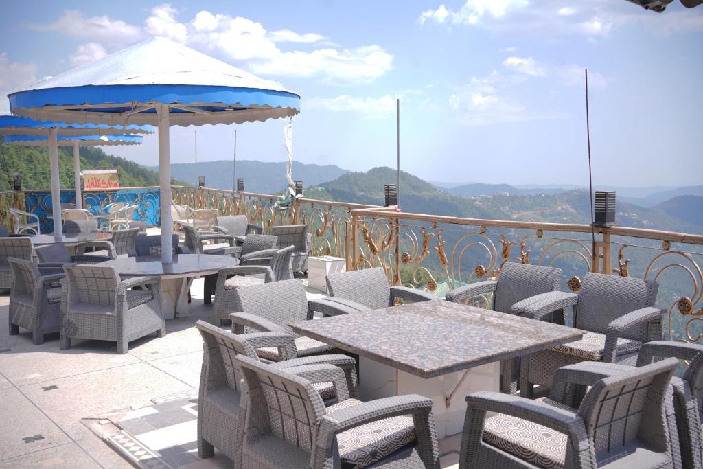 a patio with tables and chairs and an umbrella at Burj A Zafar in Murree