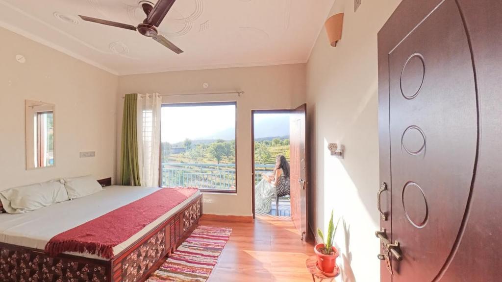a bedroom with a bed and a large window at Aahista Stays- Mountain view homestay in Bīr