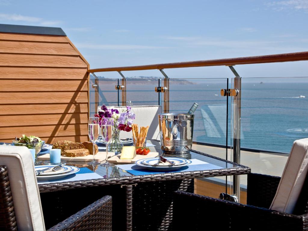 a table on a balcony with a view of the ocean at Dunlin 4 - The Cove in Brixham