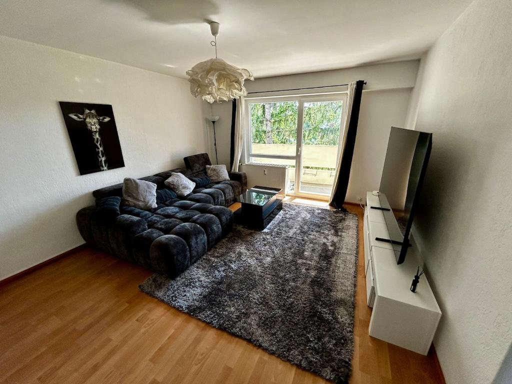 a living room with a couch and a large window at Appart cosy porte de Bâle - Terrasse - Parking - Tram in Saint-Louis
