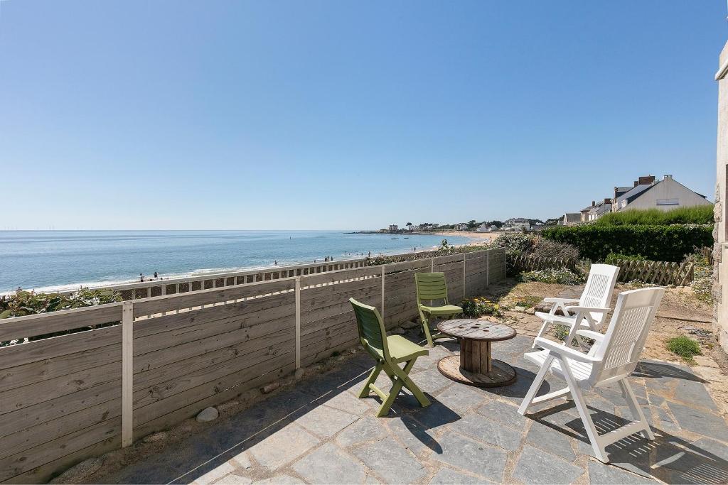 a patio with chairs and a table and the beach at Villa Timao Plage in Batz-sur-Mer