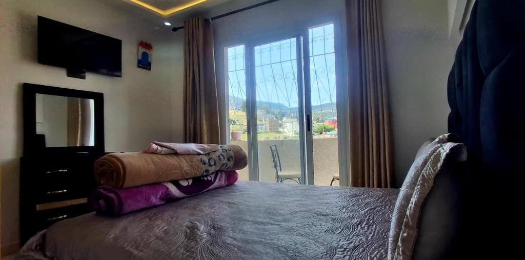 a bedroom with a bed and a large window at Casa ahlam in Chefchaouen
