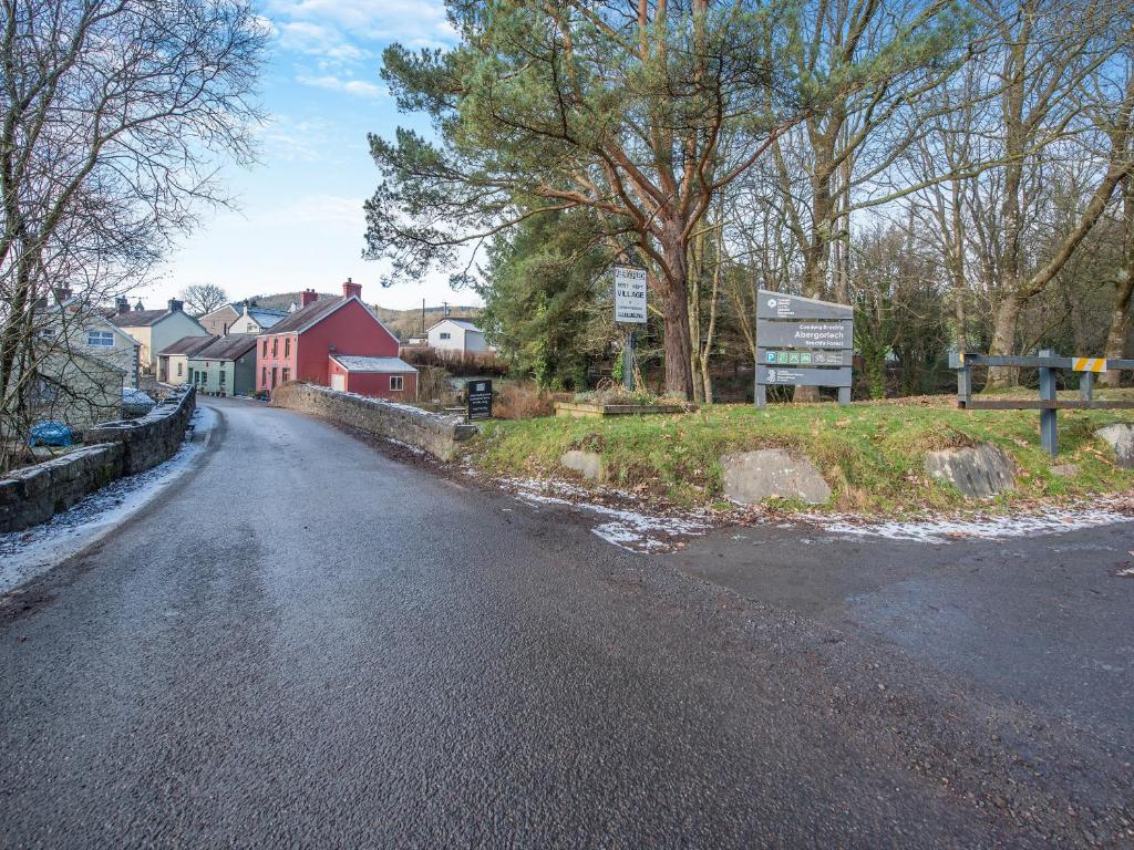 an empty road with a red house and trees at Yr Hen Efail in Abergorlech