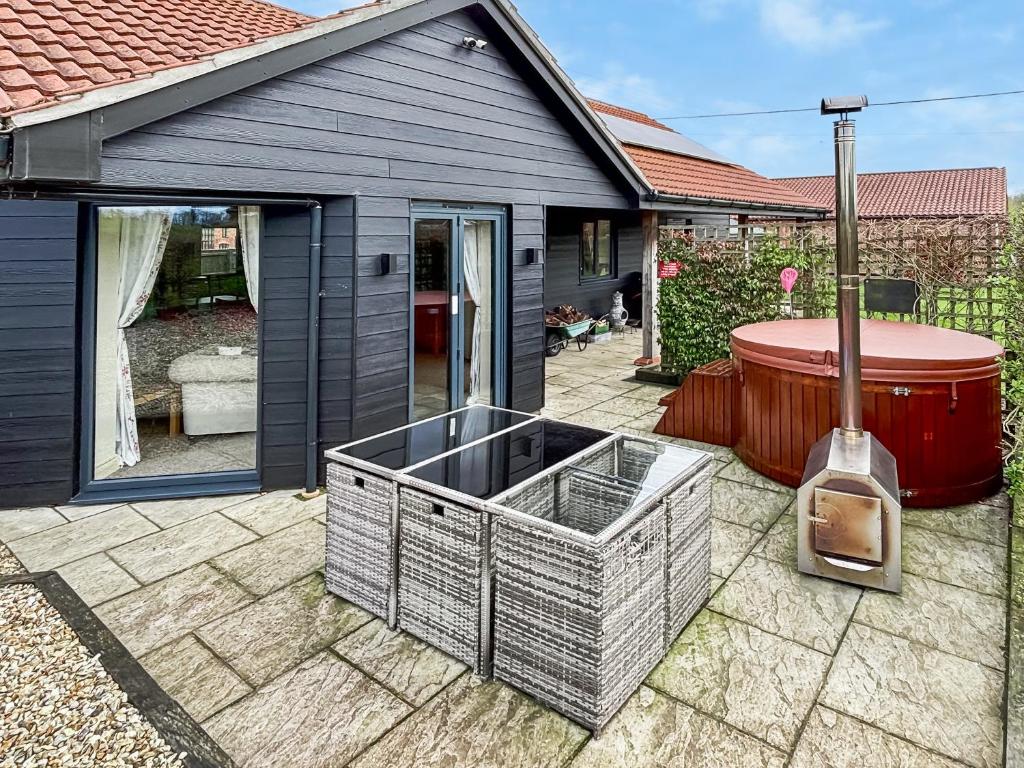 a backyard with a hot tub and a grill at Moor Farm Lodge in Bawdeswell