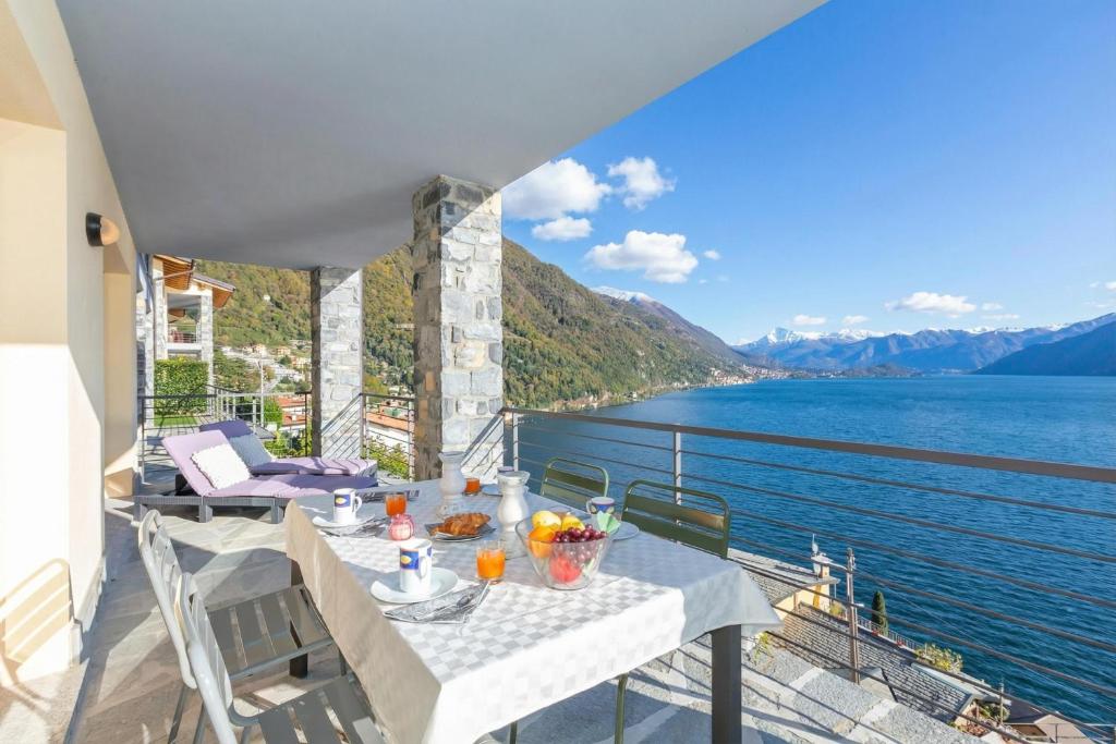 a table on a balcony with a view of the water at Residence degli Oleandri 2A in Argegno