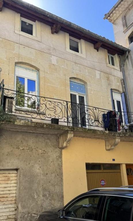 a building with a balcony and a car parked in front at Maison de ville in Pont-Saint-Esprit