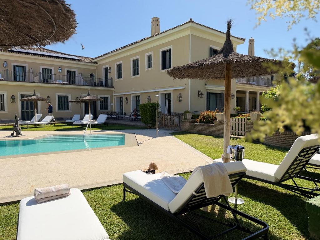 a villa with a swimming pool and chairs and an umbrella at Villa Jerez in Jerez de la Frontera