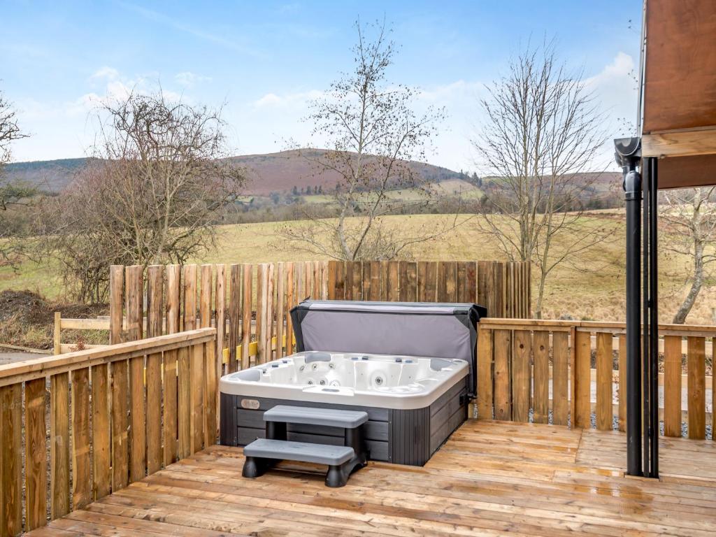 a bath tub sitting on a deck with a fence at Hawthorn Lodge - Uk42546 in Llanwrthwl