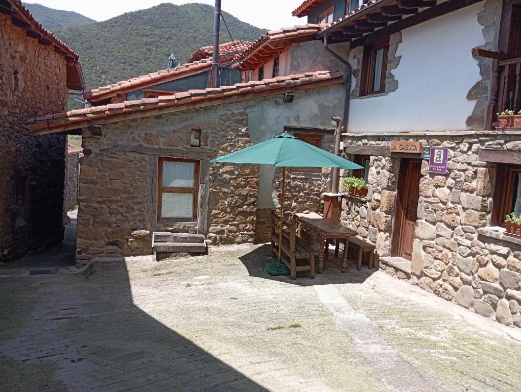a stone house with a table and an umbrella at Casas Rurales La Casuca in Ojedo