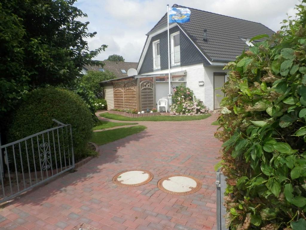a house with a brick driveway with a flag on it at Haus Ferienglueck _ Lueth in Friedrichskoog