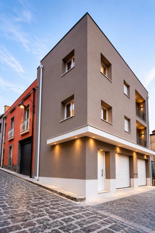 a gray building on a cobblestone street at Domus Palatium in Palazzolo Acreide