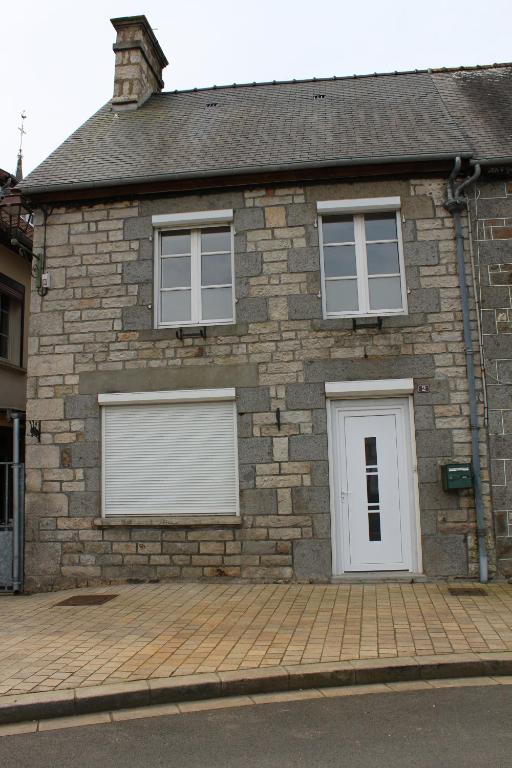 a brick house with two white garage doors at La Chandeler in Juvigny-sous-Andaine