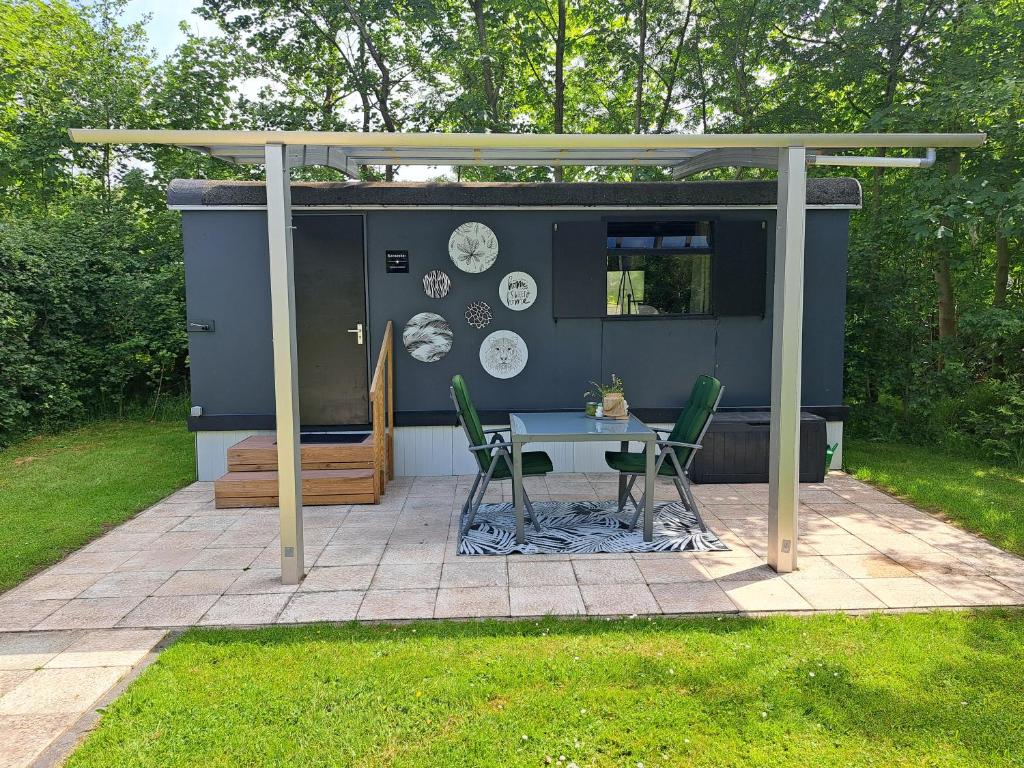 a house with a table and chairs in a yard at Camping de Zandhorst, Pipowagen Sunseeker in Wouterswoude