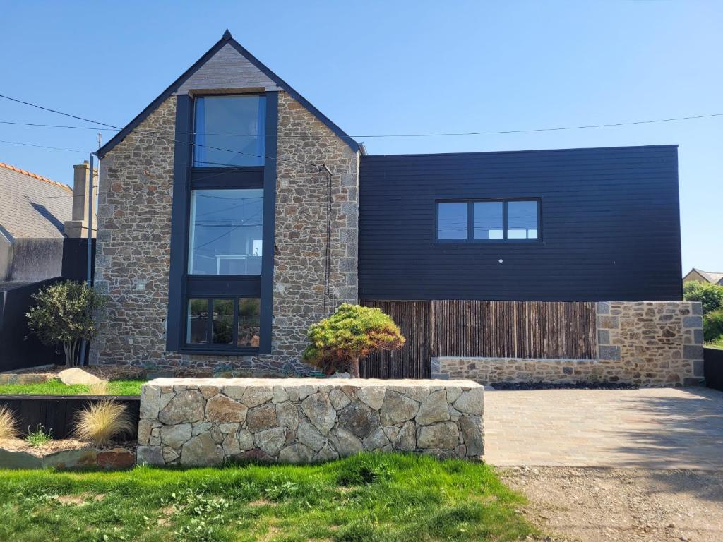 a brick house with a black roof at Villa les pepouzes - vue mer - jacuzzi- sauna in Plouescat