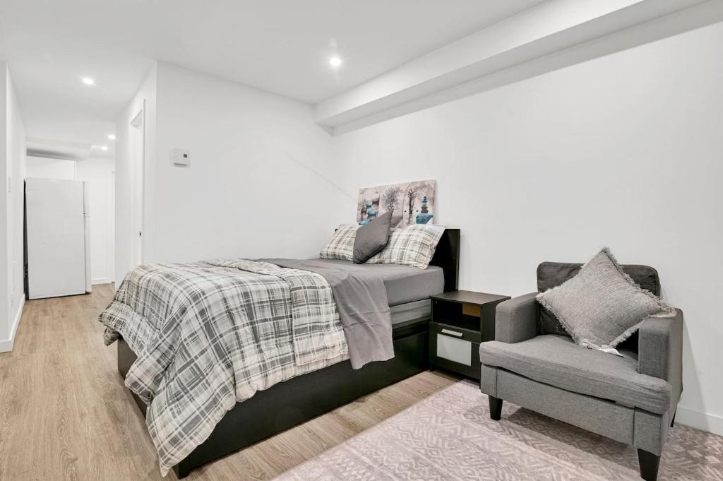 a white bedroom with a bed and a chair at Elegance comfort à Montreal in Montreal