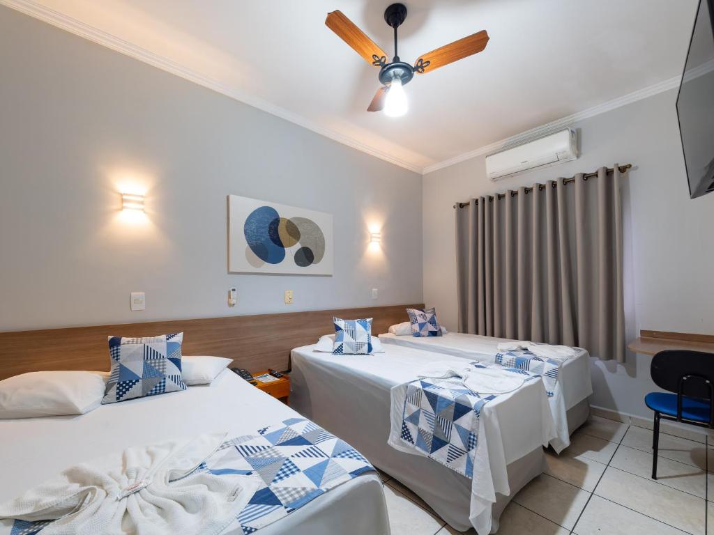 a room with two beds and a ceiling fan at Hotel Boa Vista by Carlton in Americana