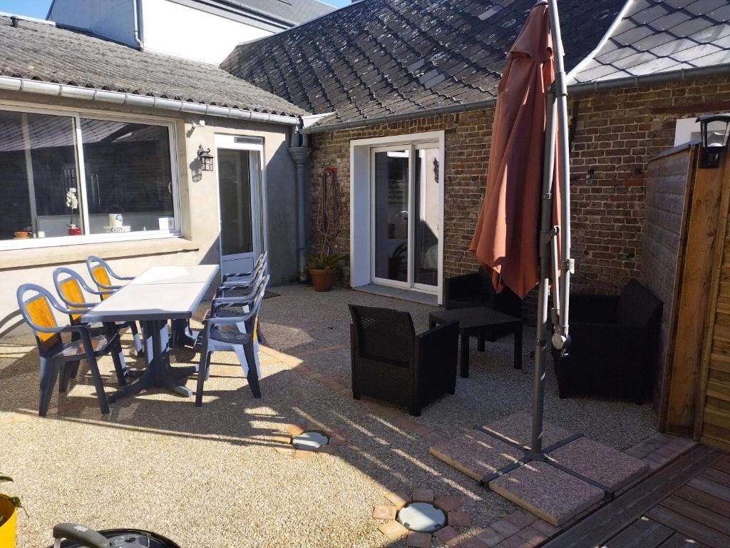 a patio with a table and chairs and an umbrella at L'Escale in Pendé