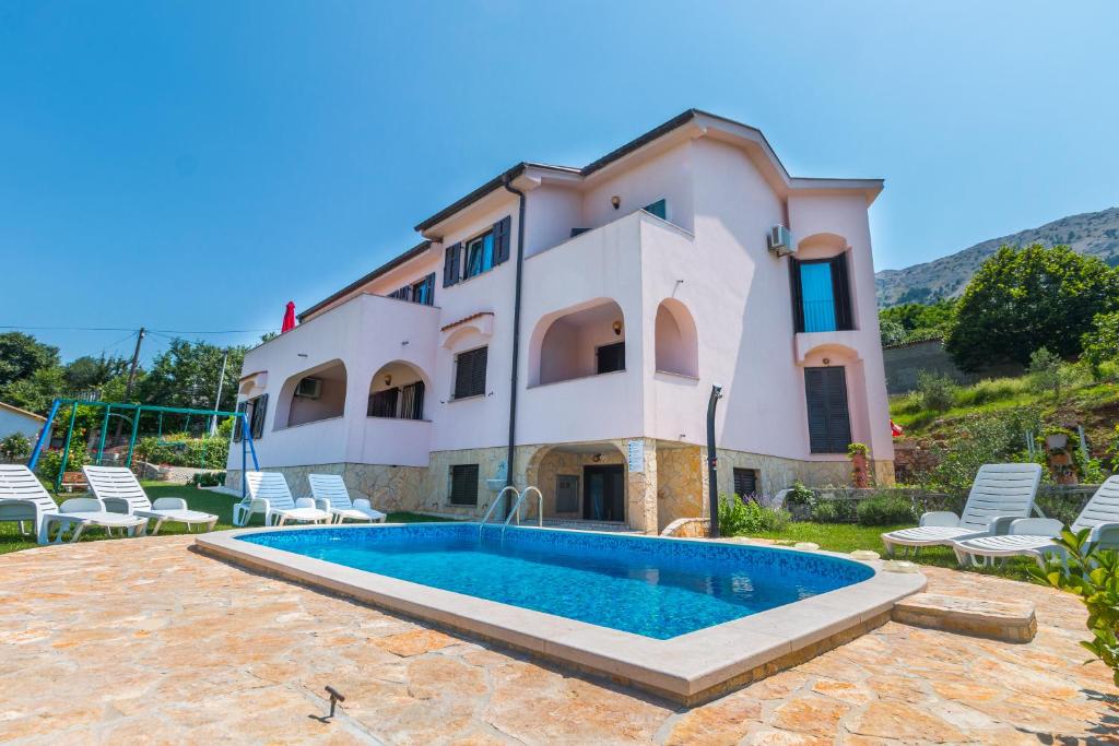 an external view of a villa with a swimming pool at Apartments Bavaria in Baška