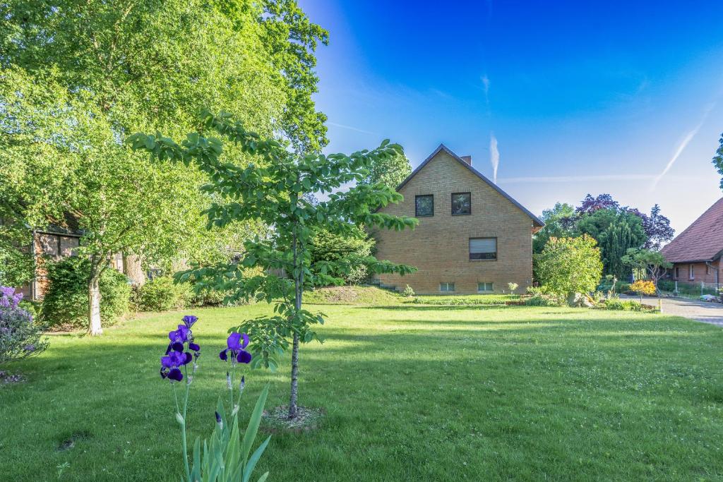 a house with a tree and purple flowers in the yard at Ferienwohnung KOTE in Dannenberg
