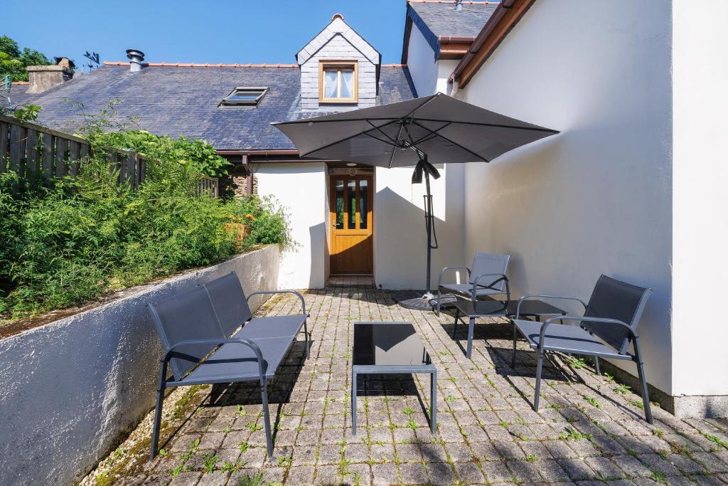 a group of chairs and an umbrella on a patio at La Poya in Plonévez-du-Faou