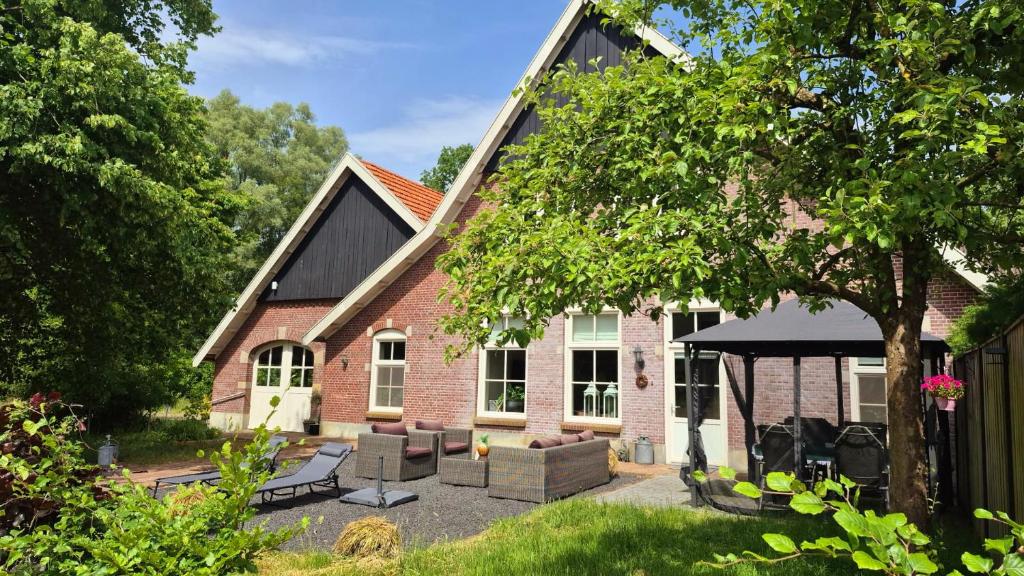 a brick house with a patio and a gazebo at Landhuis onder de lindeboom in Losser