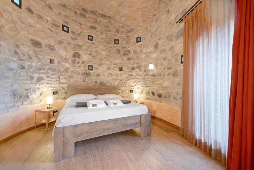a bedroom with a bed and a stone wall at Casa Dolce Casa Al Castello in Pozzolengo