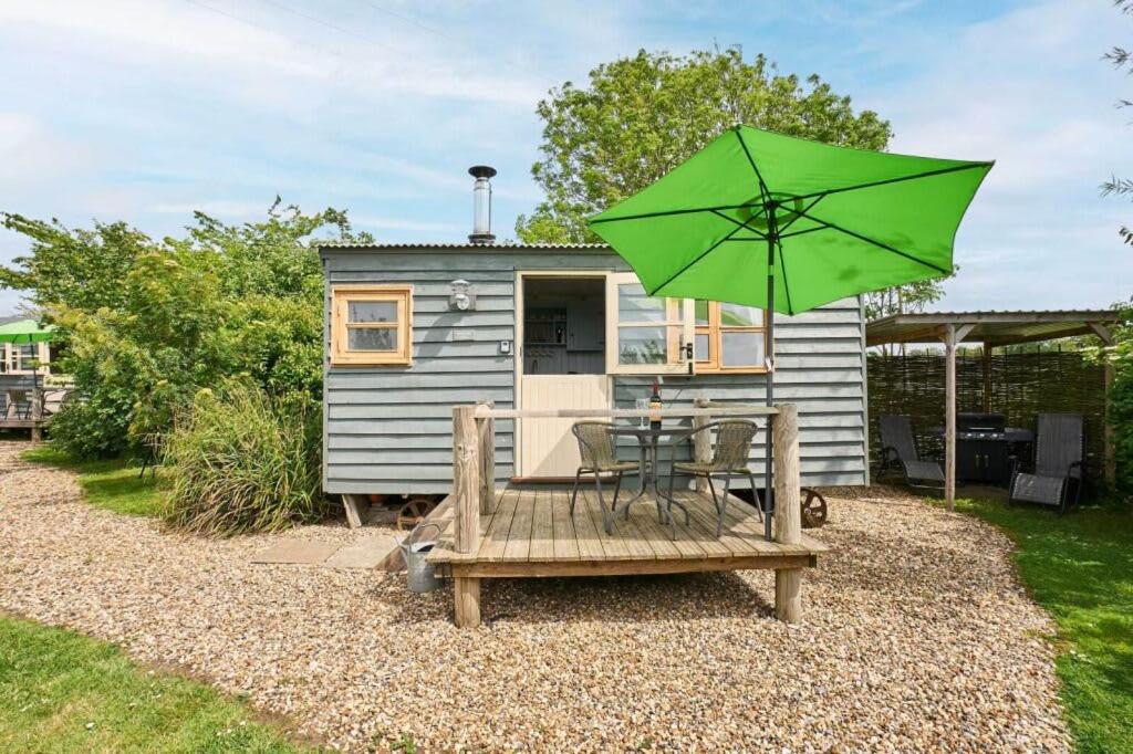a green umbrella and a table and chairs with a house at Host & Stay - Shepherds View in Alburgh