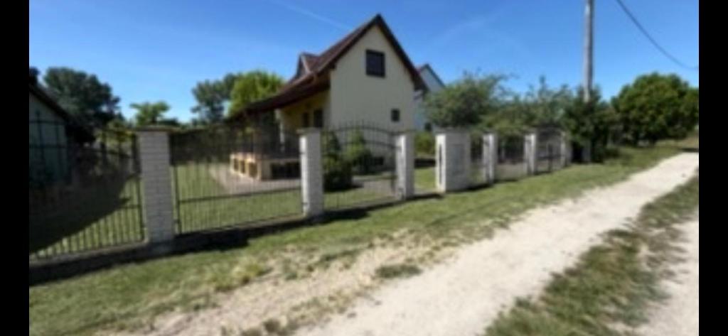 a house with a fence next to a dirt road at Stella apartman in Gabčíkovo