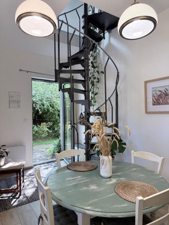 a dining room with a green table and a spiral staircase at Chez Joséphine in Gerville