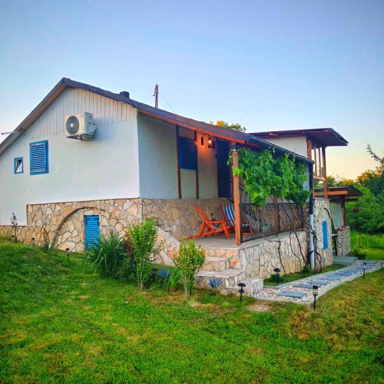 a house with a stone wall next to a yard at Kuća za odmor Veles in Orahovica
