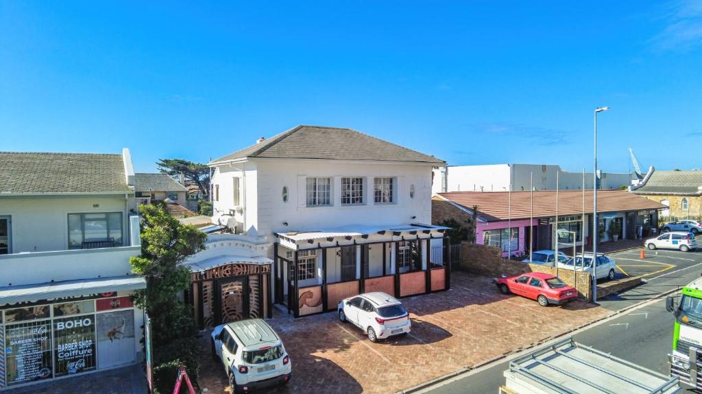 a white house with cars parked in a parking lot at Adamastor Backpackers in Muizenberg