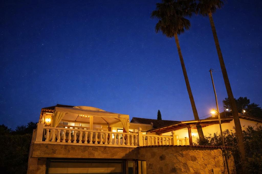 a house with a deck and a palm tree at night at Zaks House Valle San Lorenzo in Arona