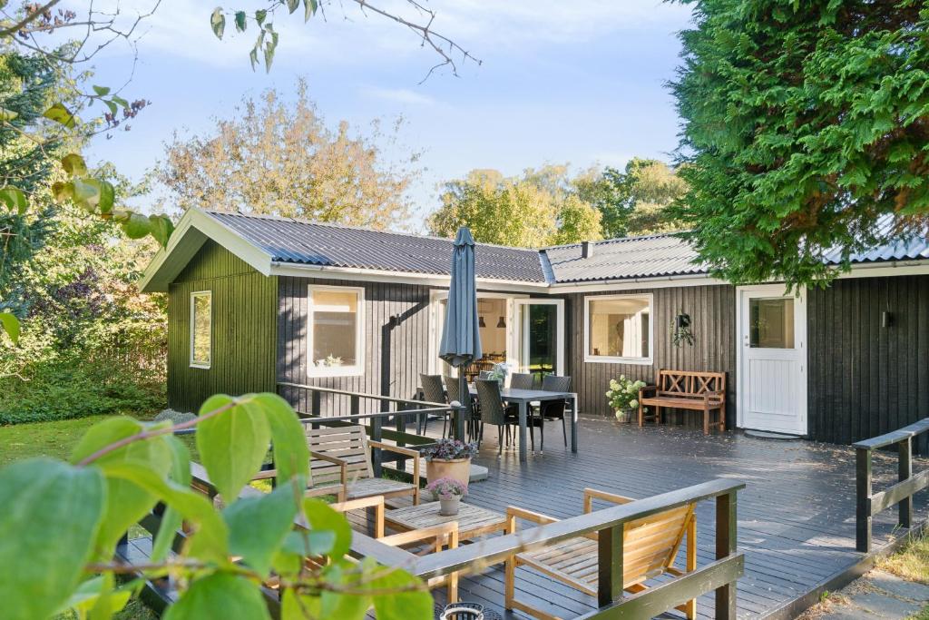 a house with a deck with a table and chairs at Newly Renovated And Modern Cottage Near The Beach in Hornbæk