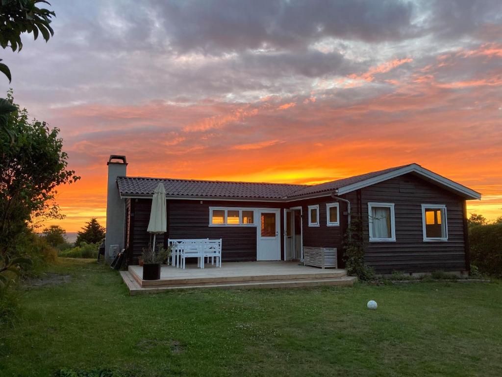 a small house with a sunset in the background at Nice Summer House With Sea View in Jægerspris