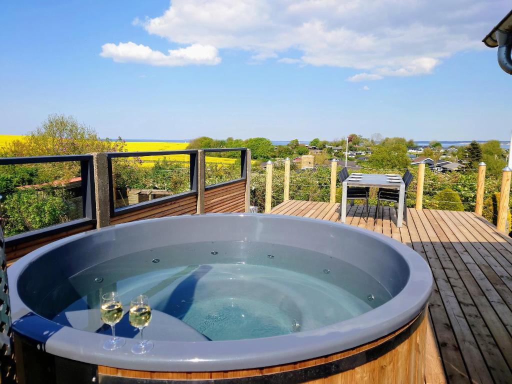a hot tub on a deck with two wine glasses at Cottage With A View in Roslev