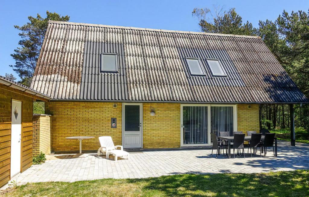 ein gelbes Backsteinhaus mit einem Tisch und Stühlen in der Unterkunft Schönes Ferienhaus Auf Bornholm Mit Meerblick in Neksø