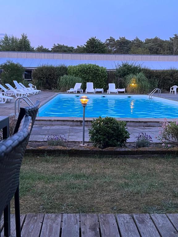 a swimming pool with chairs and a light next to it at Cozy Holiday Apartment Close To The Beach in Neksø