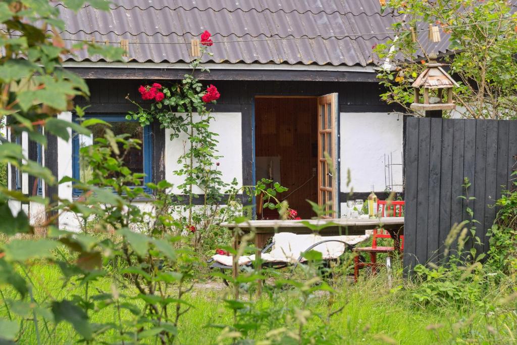 ein schwarzes Haus mit einem Tisch und Rosen davor in der Unterkunft Unique Private Idyll in Vesterborg