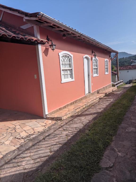 a red house with white windows and a driveway at Casa encanto das Gerais in Tiradentes