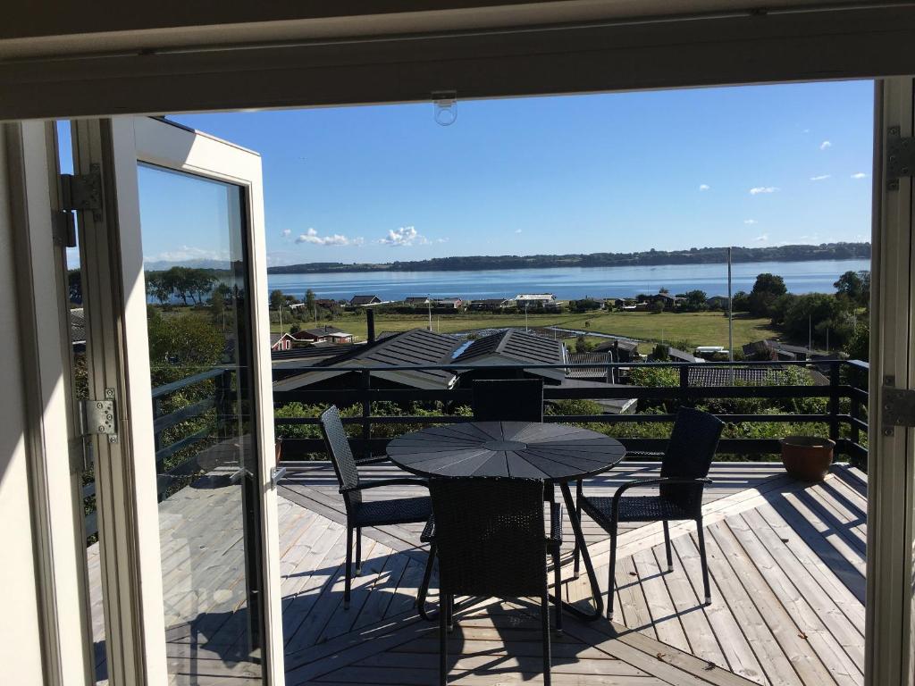 ein Balkon mit Tischen und Stühlen und Blick aufs Wasser in der Unterkunft Neu Restauriertes Sommerhaus Mit Meerblick in Aabenraa