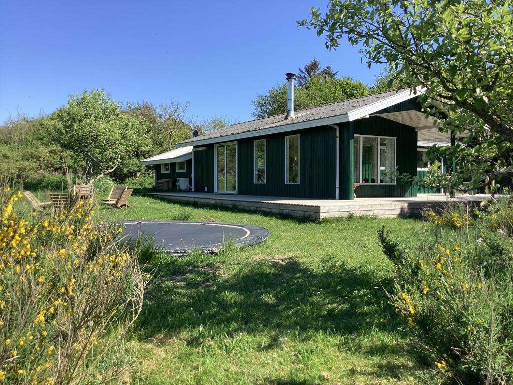a green house with a grassy yard in front of it at Peaceful Cottage By The Beach And Nature in Spottrup