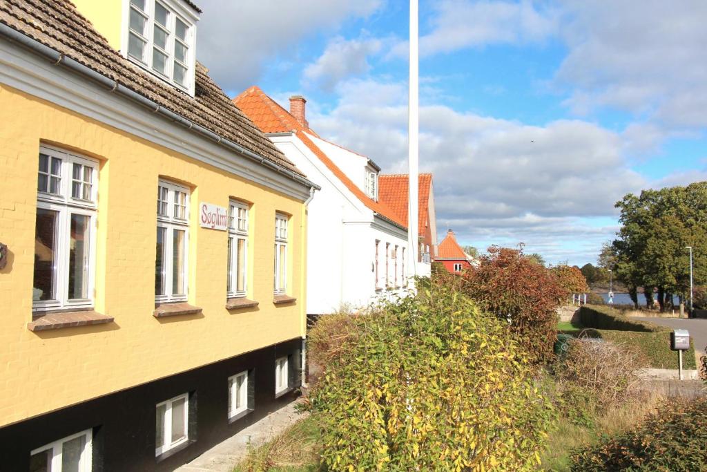 a yellow building next to a white building at Summer House In Årsdale With A Beautiful Sea View in Svaneke