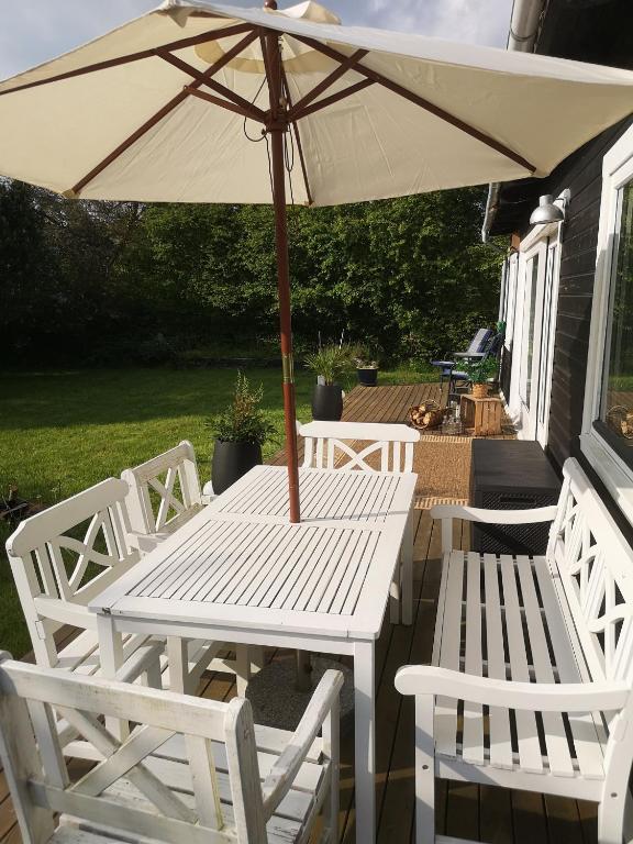 a white table and chairs with an umbrella at Beautiful Holiday Home On An Undisturbed Plot in Rødby