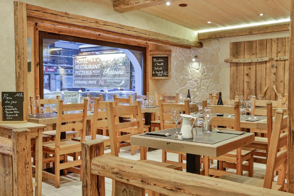 a restaurant with wooden tables and chairs and a window at Le Saint Antoine in Les Houches
